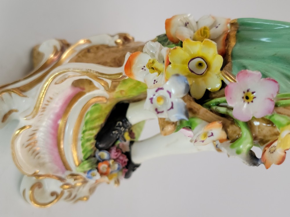 A pair of 18th-century Georgian Derby soft-paste porcelain figural candlesticks depicting a male and female figure in period dress beside candle sconces adorned with colourful flowers and gilt Rococo scrollwork. View XI