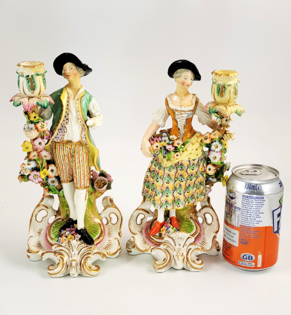 A pair of 18th-century Georgian Derby soft-paste porcelain figural candlesticks depicting a male and female figure in period dress beside candle sconces adorned with colourful flowers and gilt Rococo scrollwork. View XIII