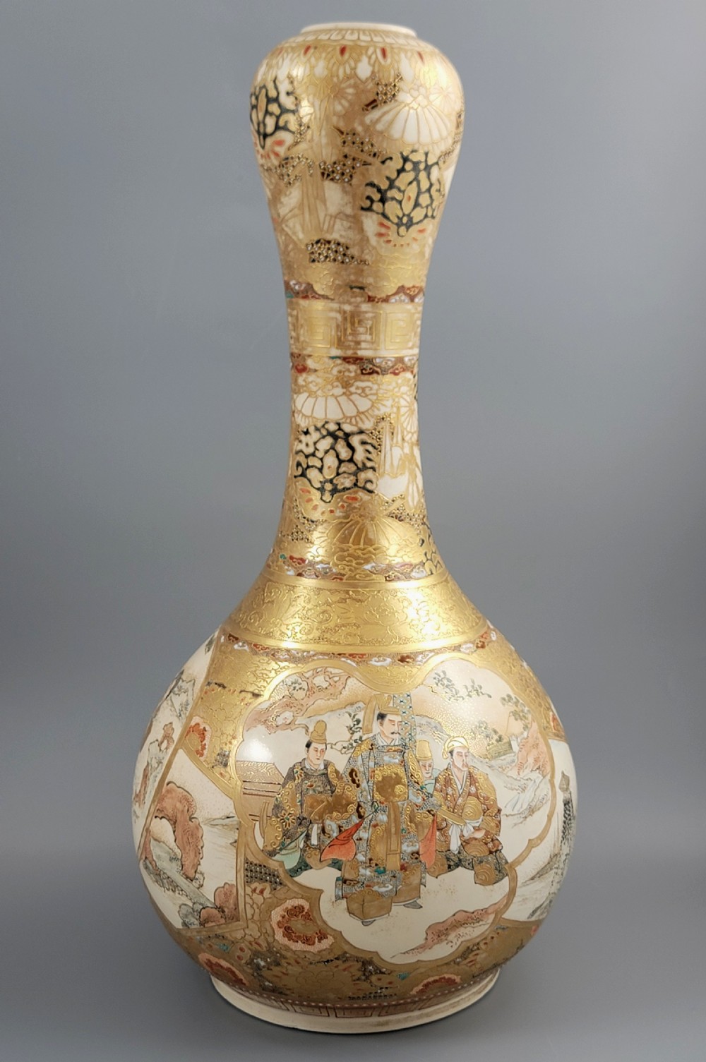 A Japanese Satsuma earthenware vase featuring a bulbous garlic-shaped mouth, intricate gilded borders, and painted panels depicting samurai warriors. View V