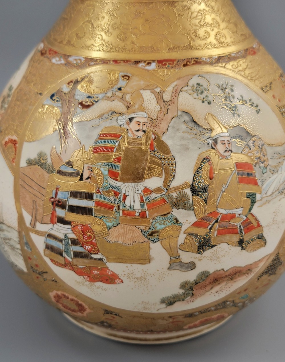A Japanese Satsuma earthenware vase featuring a bulbous garlic-shaped mouth, intricate gilded borders, and painted panels depicting samurai warriors. View VIII
