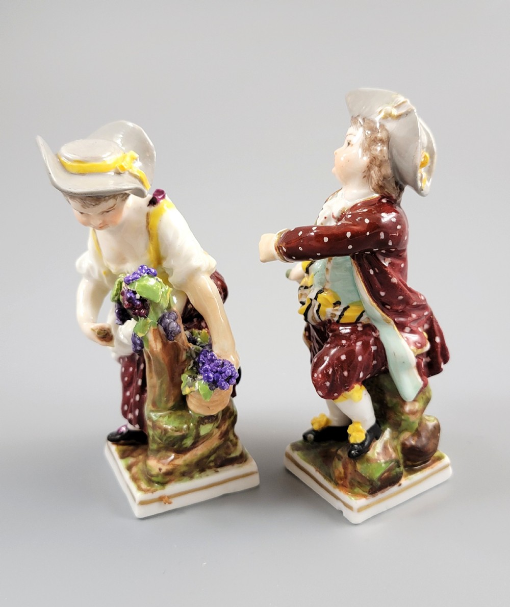 A pair of 19th-century Dresden porcelain figurines depicting a male and female grape picker in traditional attire holding baskets of purple grapes. View II