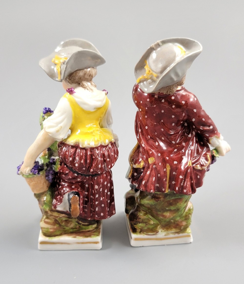A pair of 19th-century Dresden porcelain figurines depicting a male and female grape picker in traditional attire holding baskets of purple grapes. View III