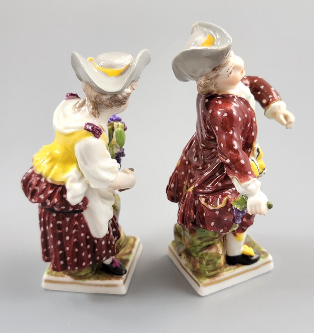 A pair of 19th-century Dresden porcelain figurines depicting a male and female grape picker in traditional attire holding baskets of purple grapes. View IV