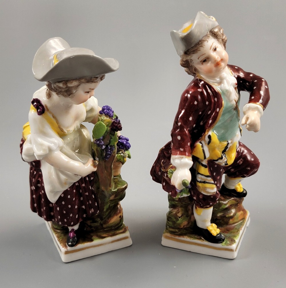 A pair of 19th-century Dresden porcelain figurines depicting a male and female grape picker in traditional attire holding baskets of purple grapes. View V