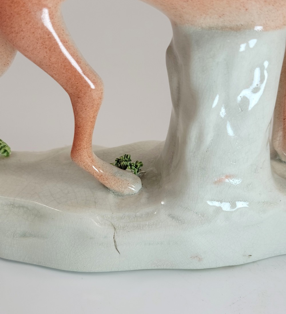 A pair of Victorian Staffordshire earthenware greyhound figurines standing on white bases with caught hares held in their mouths. View VIII