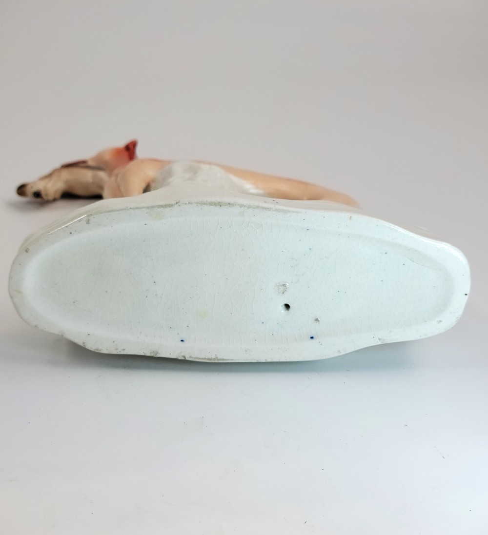 A pair of Victorian Staffordshire earthenware greyhound figurines standing on white bases with caught hares held in their mouths. View IX