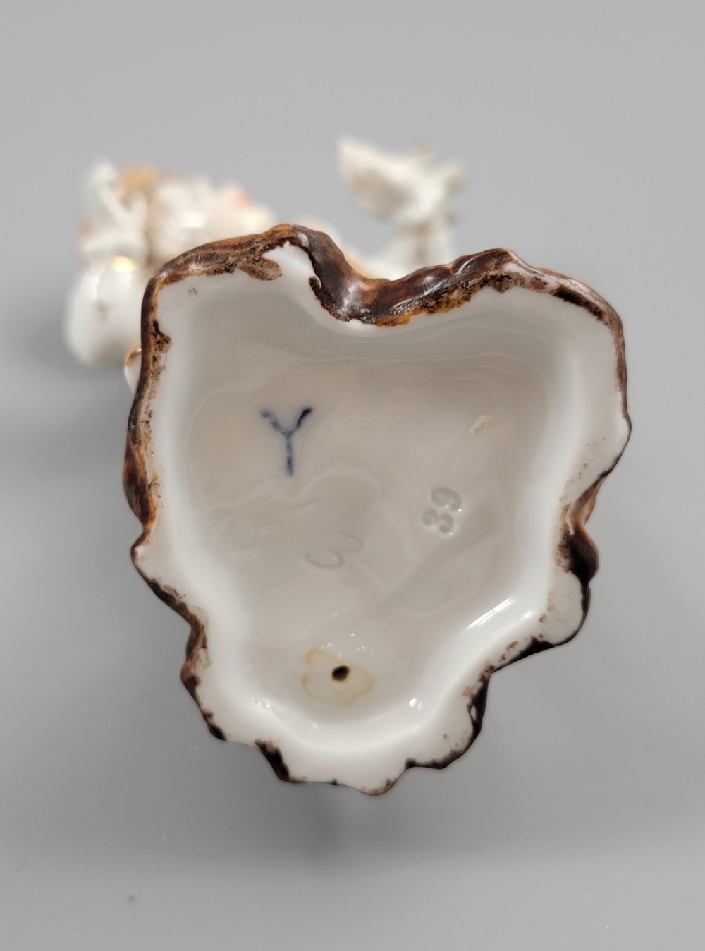 An antique German porcelain figurine depicting a boy wearing a floral coat and holding a small bird on his hand. View VIII