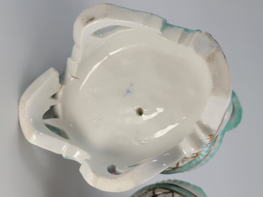A pair of 19th-century German porcelain sweetmeat figures featuring sculpted children with birds beside reticulated baskets on ornate scrollwork bases. View VIII