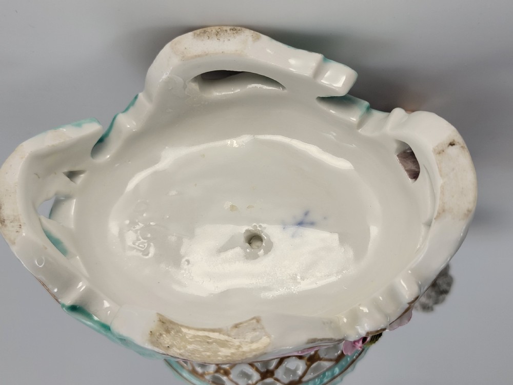 A pair of 19th-century German porcelain sweetmeat figures featuring sculpted children with birds beside reticulated baskets on ornate scrollwork bases. View IX