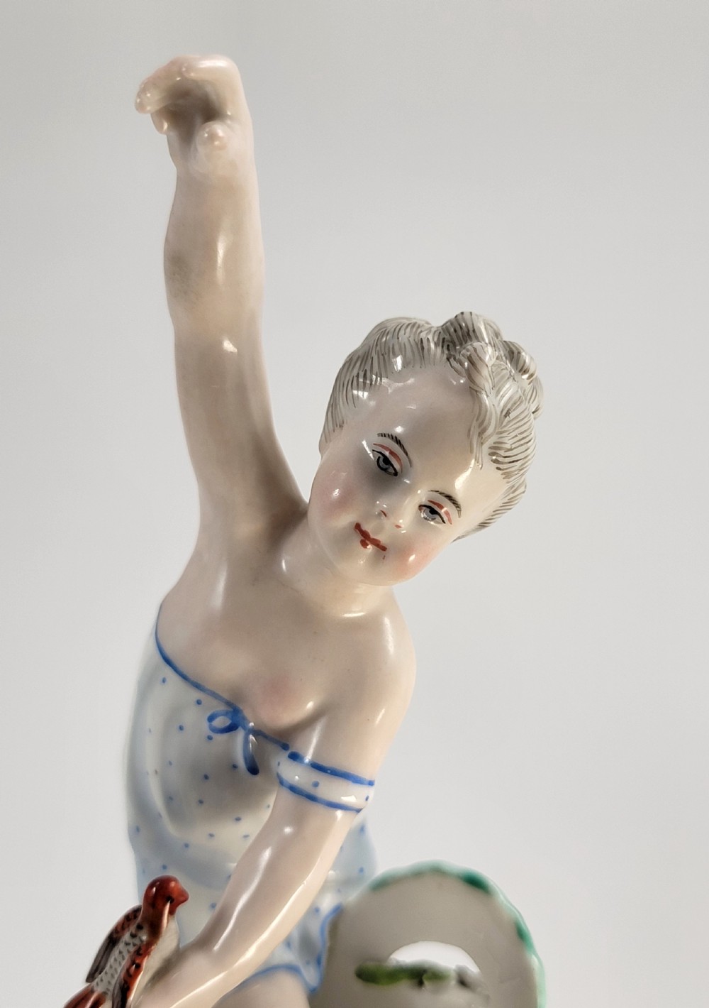A pair of 19th-century German porcelain sweetmeat figures featuring sculpted children with birds beside reticulated baskets on ornate scrollwork bases. View XI