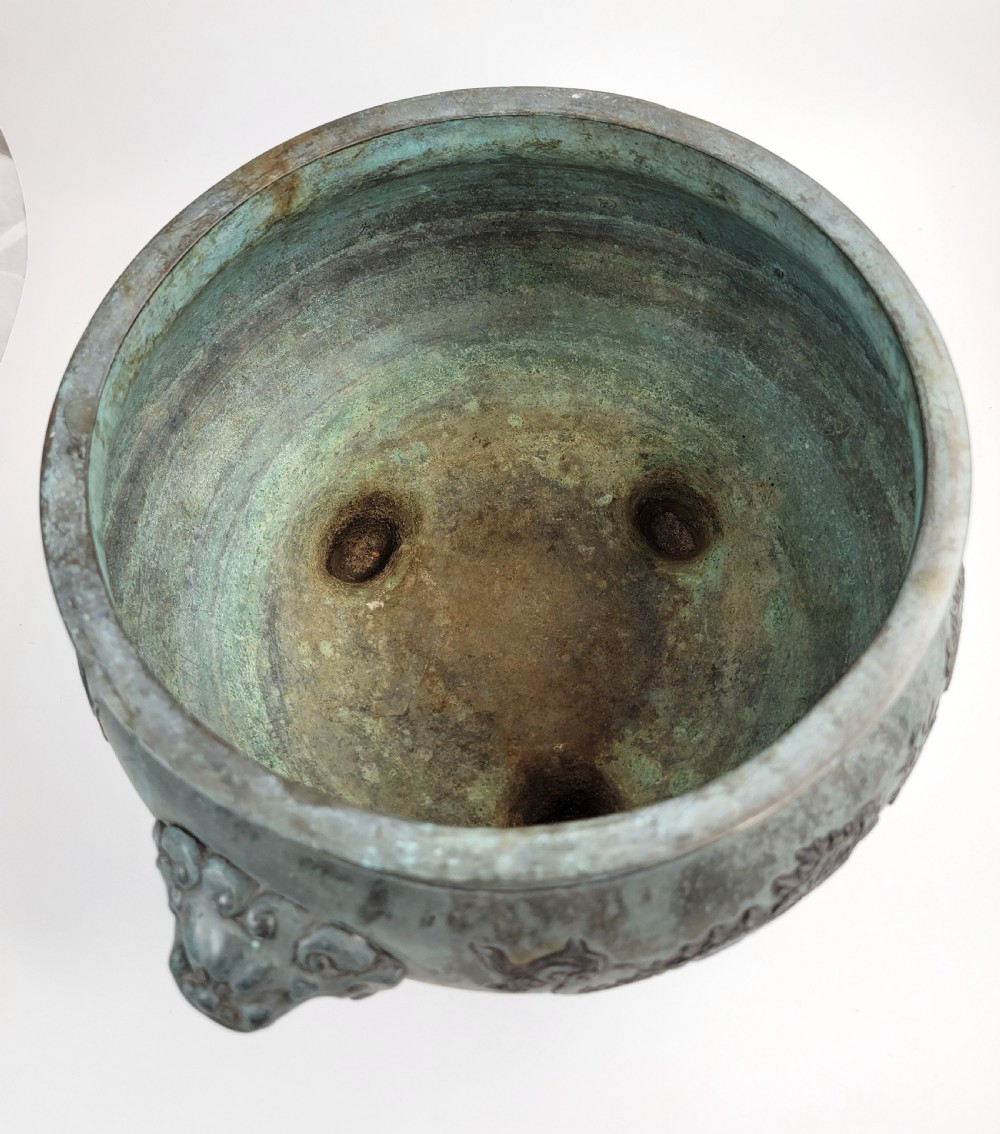 A tripod Chinese bronze censer decorated with raised dragon motifs, mask handles, and a verdigris surface finish. View XI