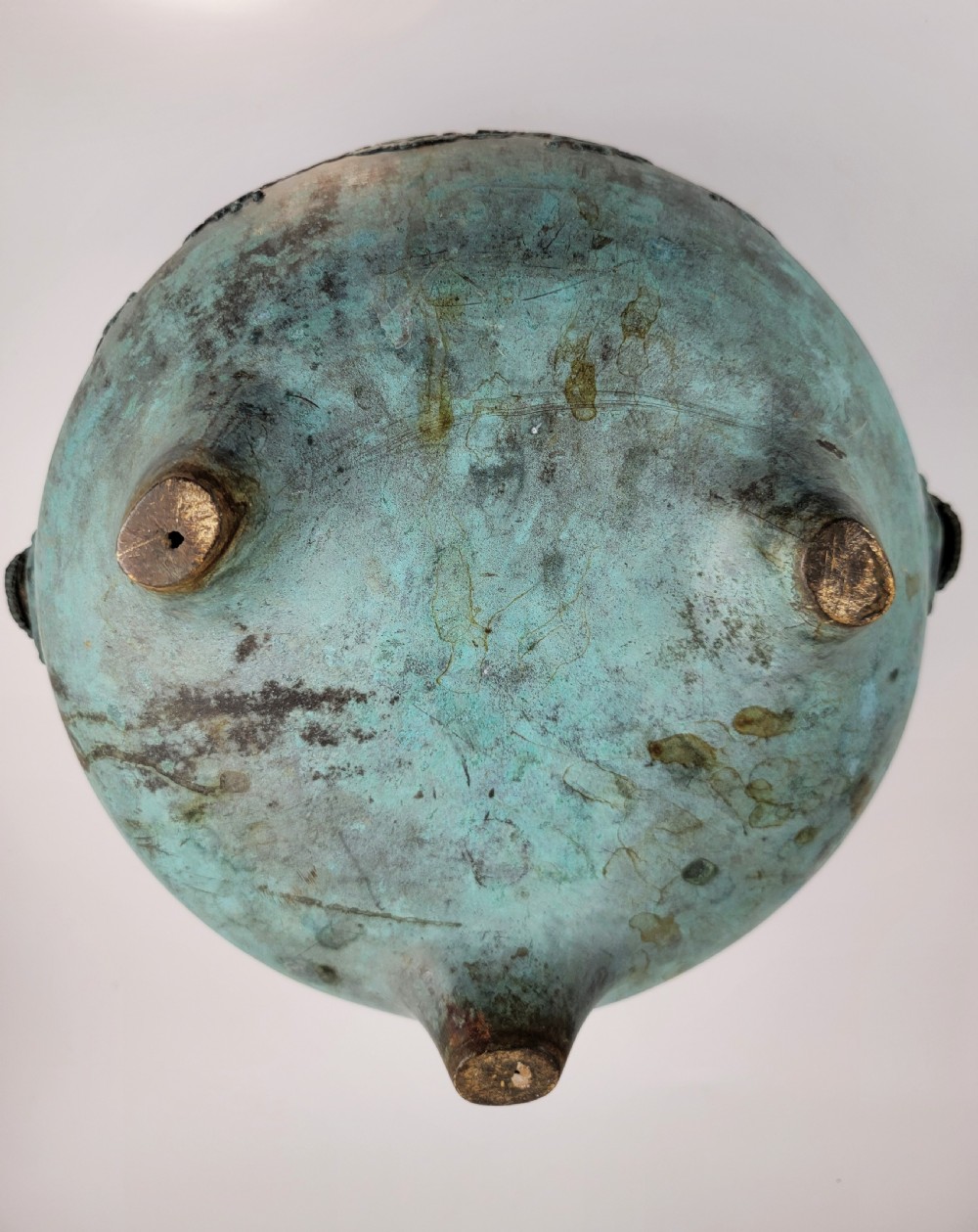 A tripod Chinese bronze censer decorated with raised dragon motifs, mask handles, and a verdigris surface finish. View XIII