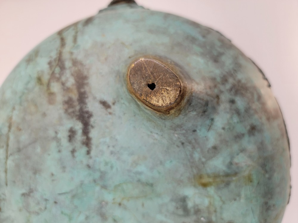 A tripod Chinese bronze censer decorated with raised dragon motifs, mask handles, and a verdigris surface finish. View XIV