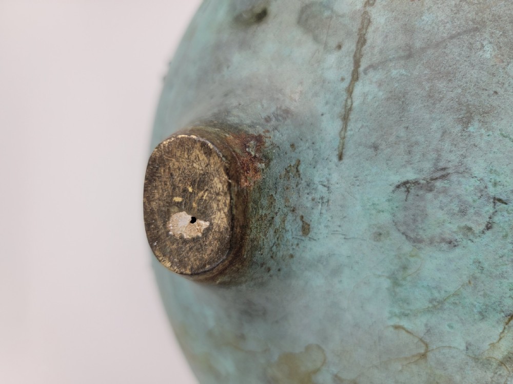 A tripod Chinese bronze censer decorated with raised dragon motifs, mask handles, and a verdigris surface finish. View XVI