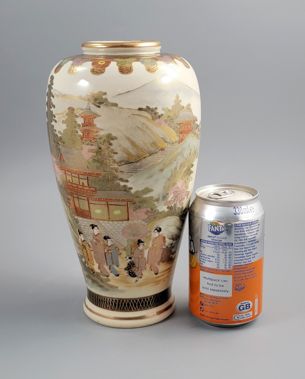 An antique Japanese Satsuma earthenware vase decorated with hand-painted landscape scenes, figures, and pagodas over a fine crackle glaze, sitting on a turned dark wood stand. View XI