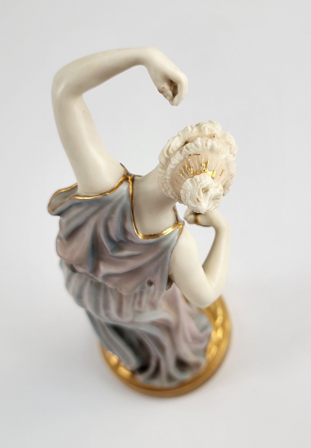 A Royal Worcester porcelain figurine depicting a draped female figure in classical robes performing a dance with small cymbals on a gilded base. View VII