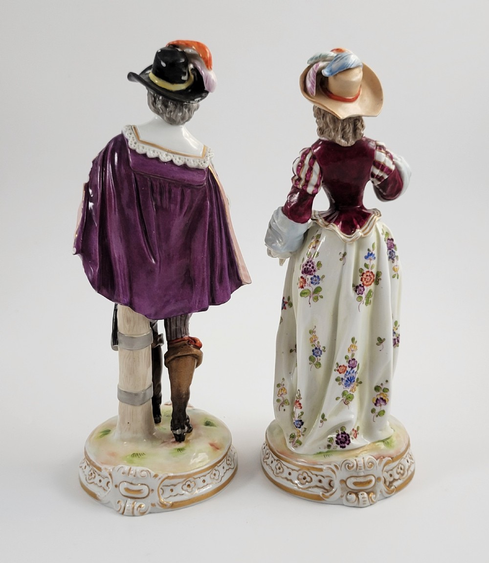 A pair of 18th-century hand-painted Ludwigsburg porcelain figures depicting a musketeer and a lady in detailed period attire standing on gilded Rococo scrollwork bases. View III