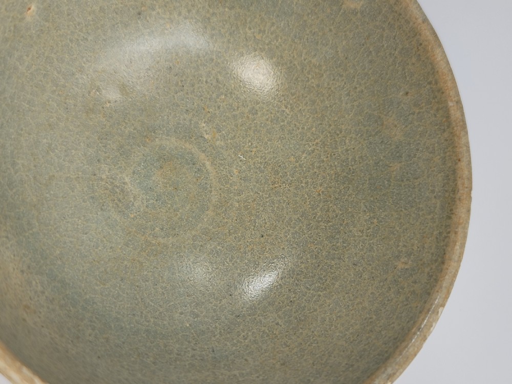 A pale green celadon ceramic bowl with carved exterior lotus petal fluting displayed on a dark carved wooden stand. View VIII