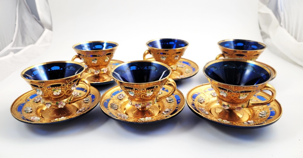 A set of six late nineteenth-century cobalt blue Bohemian glass tea cups and saucers featuring heavy gold gilding and raised enamel floral decoration.