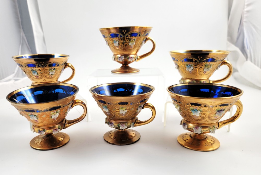 A set of six late nineteenth-century cobalt blue Bohemian glass tea cups and saucers featuring heavy gold gilding and raised enamel floral decoration. View XI