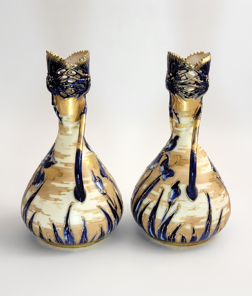 A pair of Art Nouveau porcelain vases featuring hand-painted cobalt blue iris flowers, gold-toned striped backgrounds, and gilded sweeping handles. View II