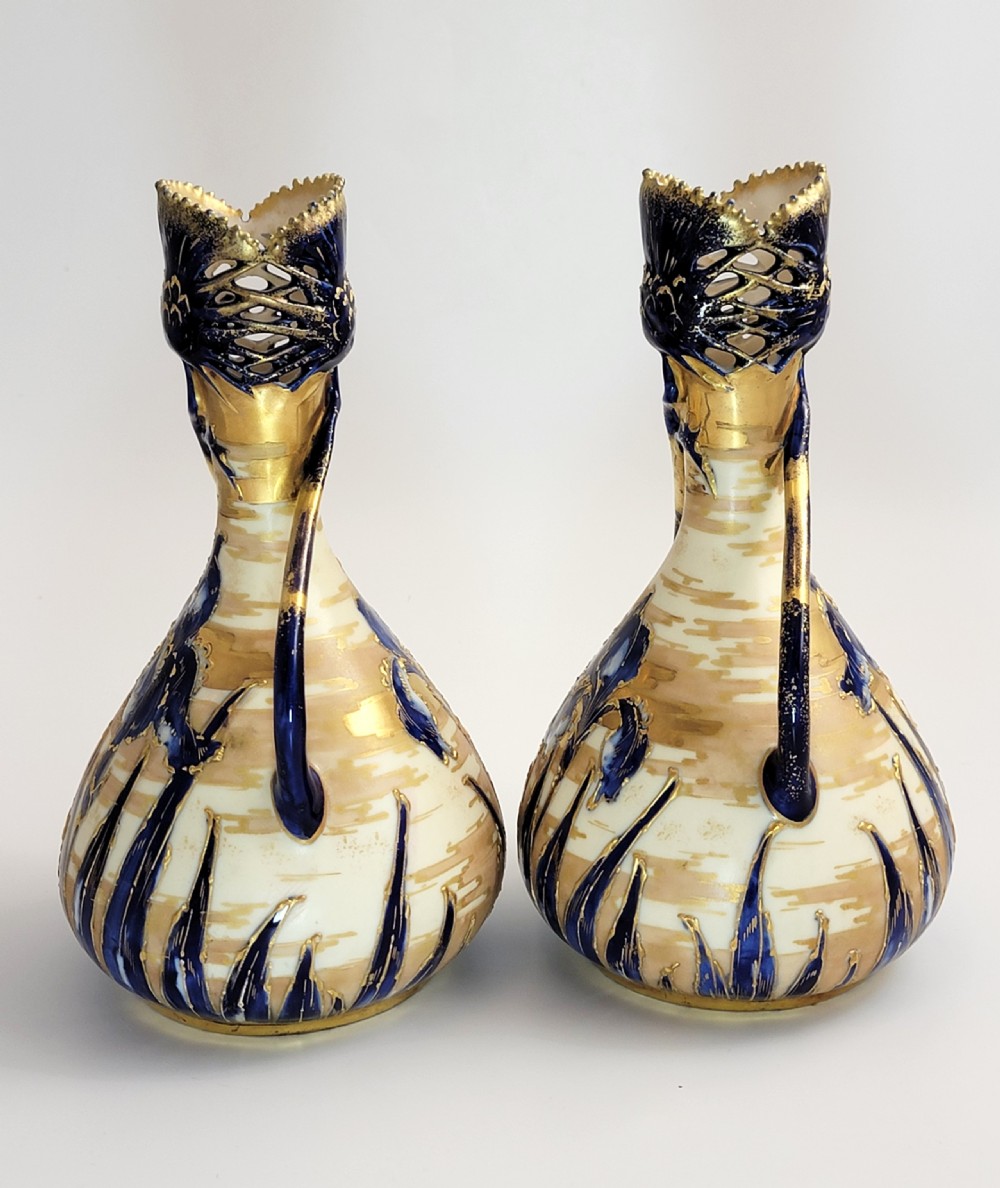 A pair of Art Nouveau porcelain vases featuring hand-painted cobalt blue iris flowers, gold-toned striped backgrounds, and gilded sweeping handles. View IV