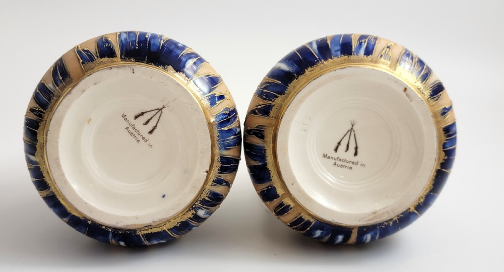A pair of Art Nouveau porcelain vases featuring hand-painted cobalt blue iris flowers, gold-toned striped backgrounds, and gilded sweeping handles. View V