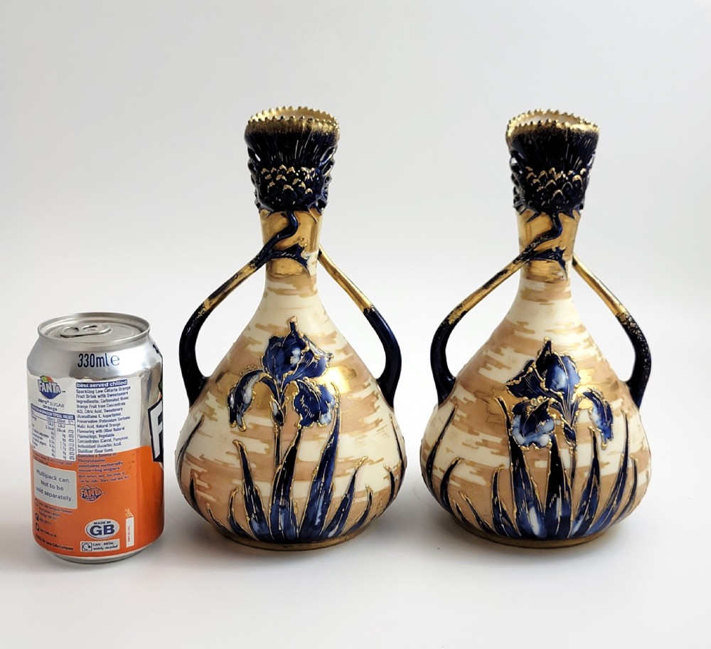 A pair of Art Nouveau porcelain vases featuring hand-painted cobalt blue iris flowers, gold-toned striped backgrounds, and gilded sweeping handles. View VI