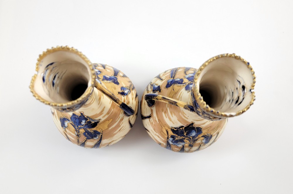 A pair of Art Nouveau porcelain vases featuring hand-painted cobalt blue iris flowers, gold-toned striped backgrounds, and gilded sweeping handles. View VII