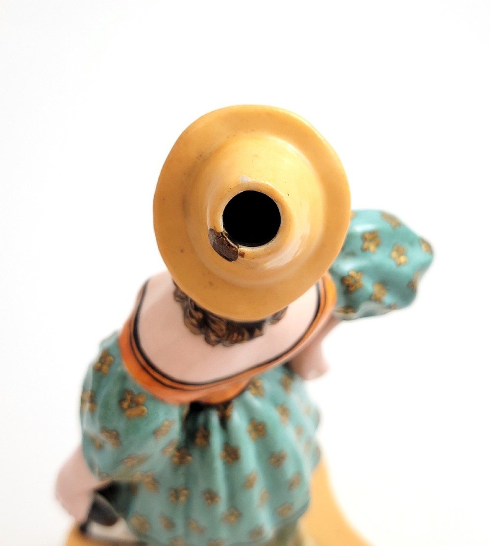 An early 19th-century French hard-paste porcelain figural scent bottle depicting a standing woman in a teal patterned dress, orange bodice, and yellow hat, mounted on a gilded shaped base. View VIII