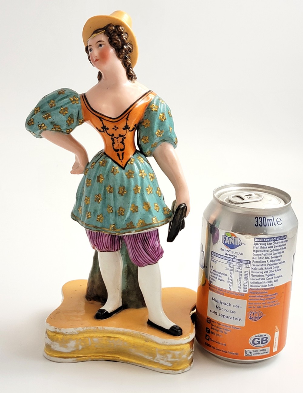An early 19th-century French hard-paste porcelain figural scent bottle depicting a standing woman in a teal patterned dress, orange bodice, and yellow hat, mounted on a gilded shaped base. View XI