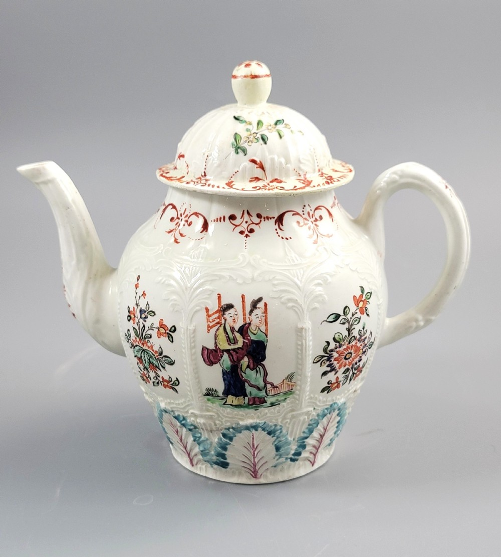 A Georgian soft-paste porcelain teapot decorated with hand-painted Chinoiserie figures, floral sprays, and moulded leaf work around the base.