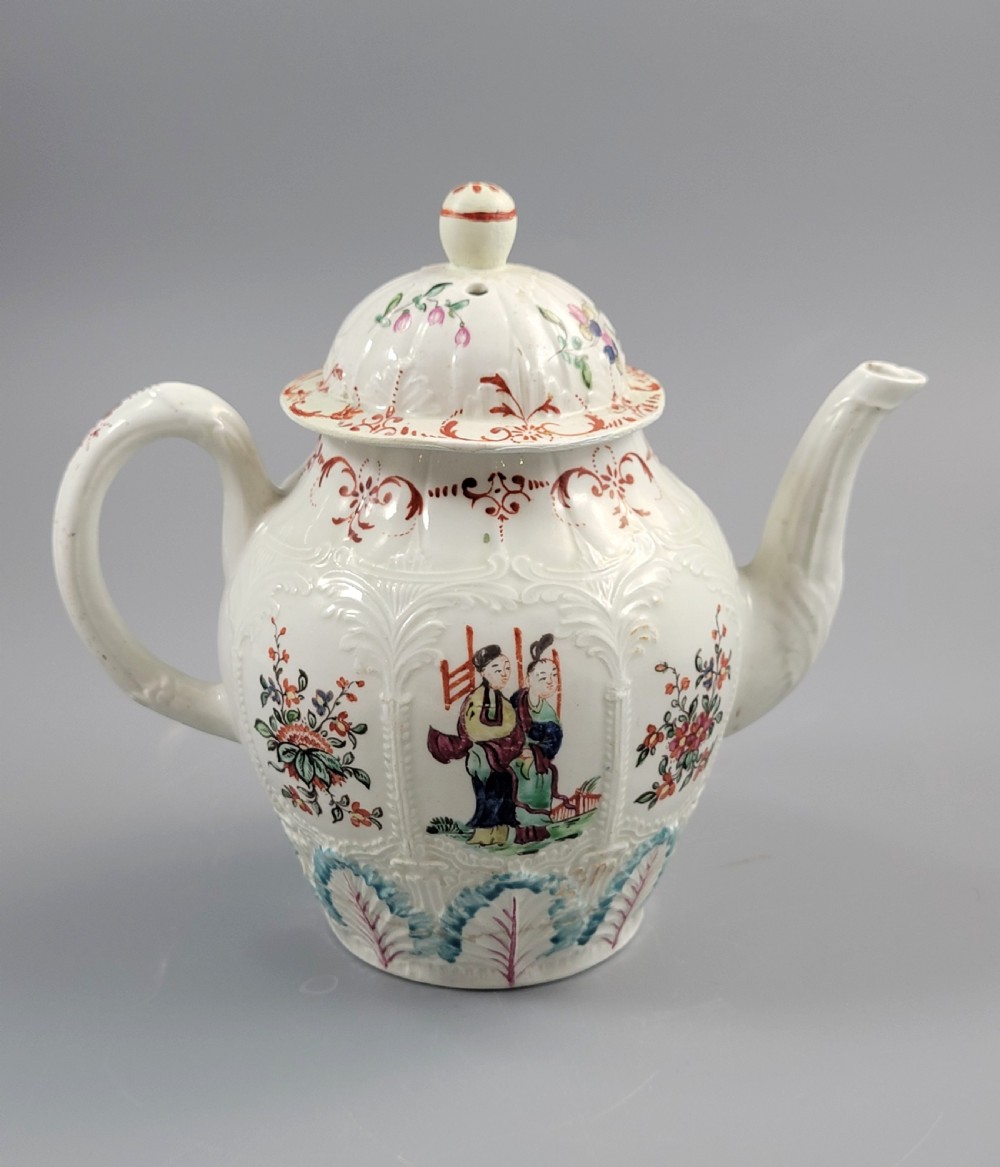 A Georgian soft-paste porcelain teapot decorated with hand-painted Chinoiserie figures, floral sprays, and moulded leaf work around the base. View IV