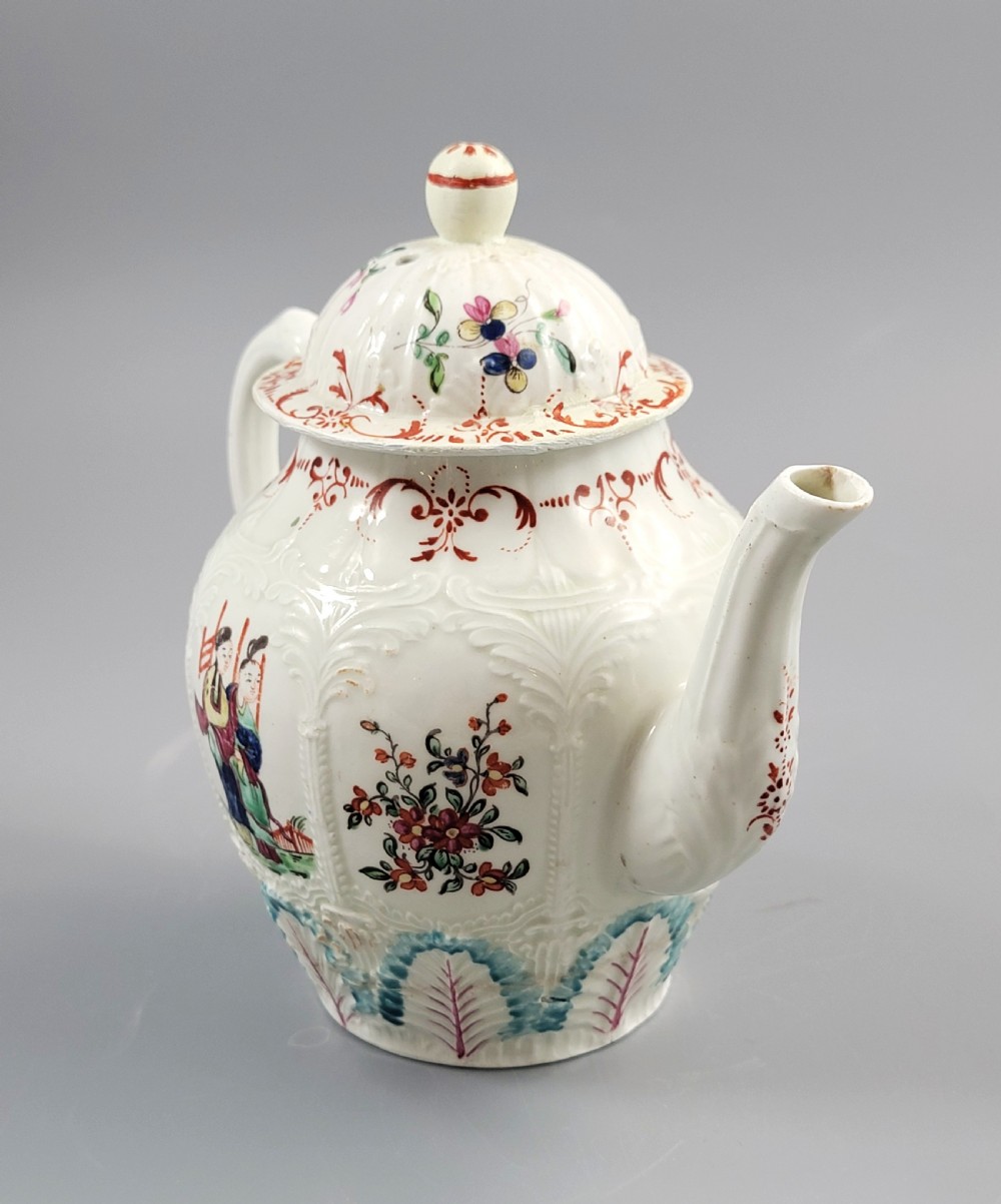 A Georgian soft-paste porcelain teapot decorated with hand-painted Chinoiserie figures, floral sprays, and moulded leaf work around the base. View V