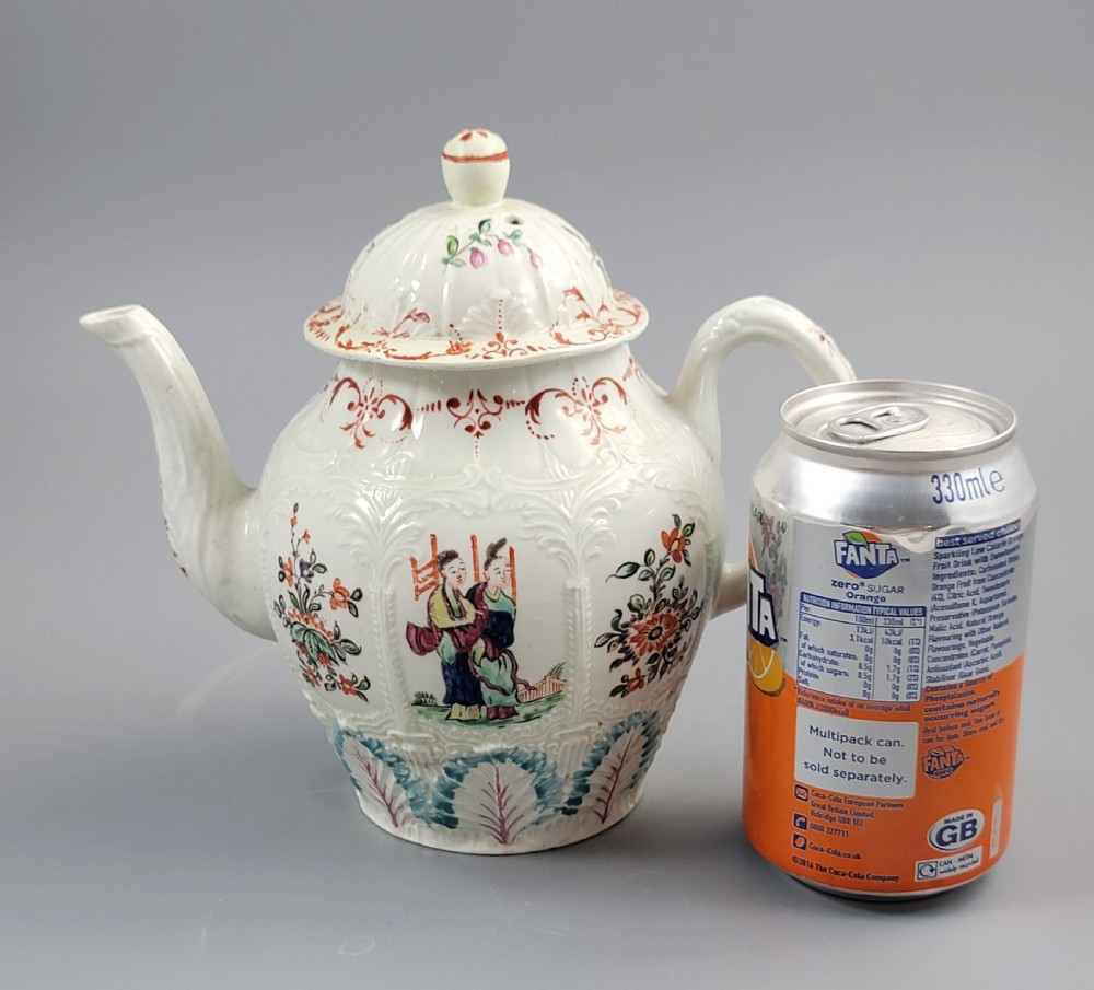 A Georgian soft-paste porcelain teapot decorated with hand-painted Chinoiserie figures, floral sprays, and moulded leaf work around the base. View XIX