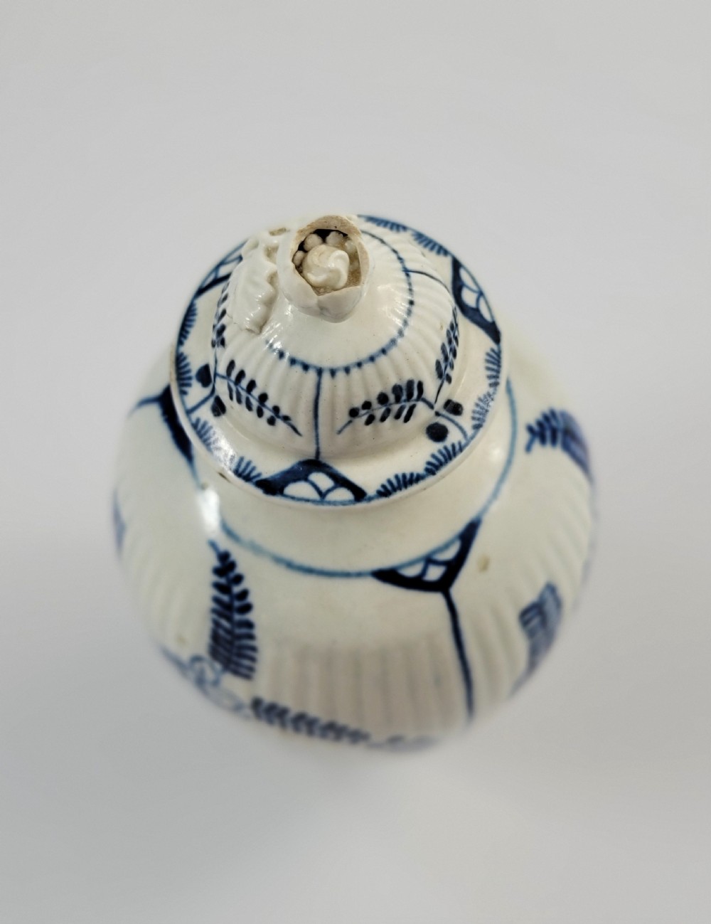 An eighteenth-century fluted soft-paste porcelain tea canister featuring underglaze blue floral patterns and a matching lid with a flower bud finial. View VIII