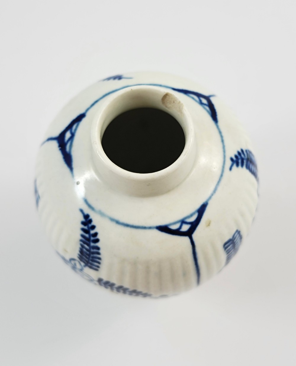 An eighteenth-century fluted soft-paste porcelain tea canister featuring underglaze blue floral patterns and a matching lid with a flower bud finial. View IX