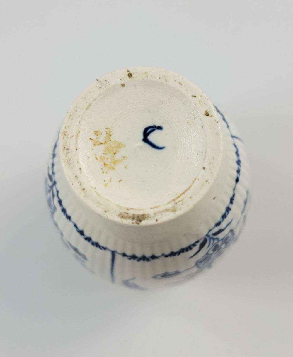 An eighteenth-century fluted soft-paste porcelain tea canister featuring underglaze blue floral patterns and a matching lid with a flower bud finial. View X