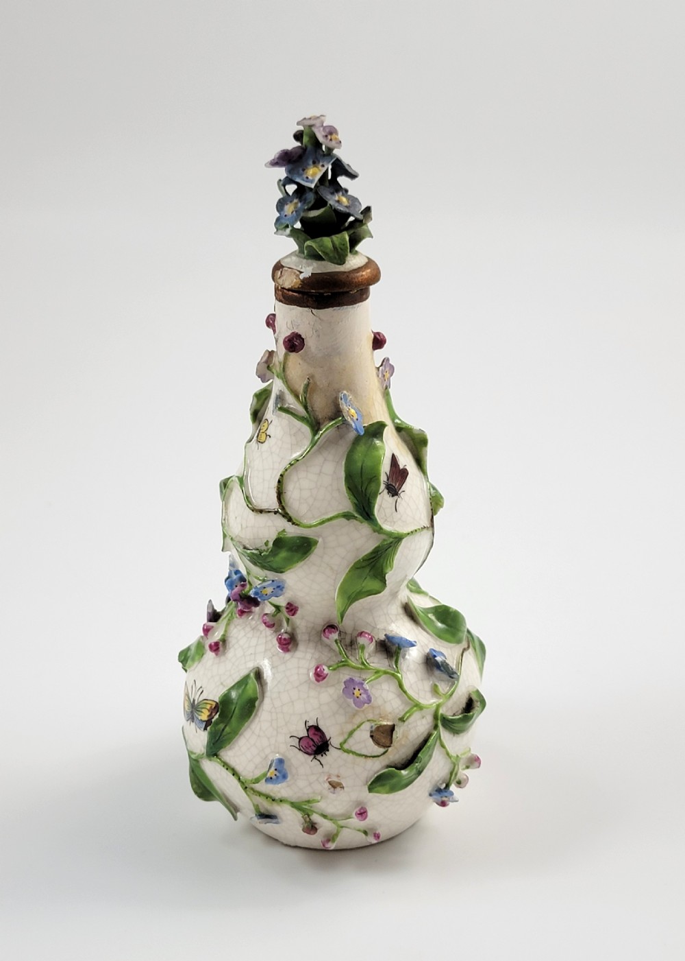A gourd-shaped white porcelain scent bottle decorated with applied forget-me-not flowers, green vines, hand-painted insects, and a floral stopper. View IV