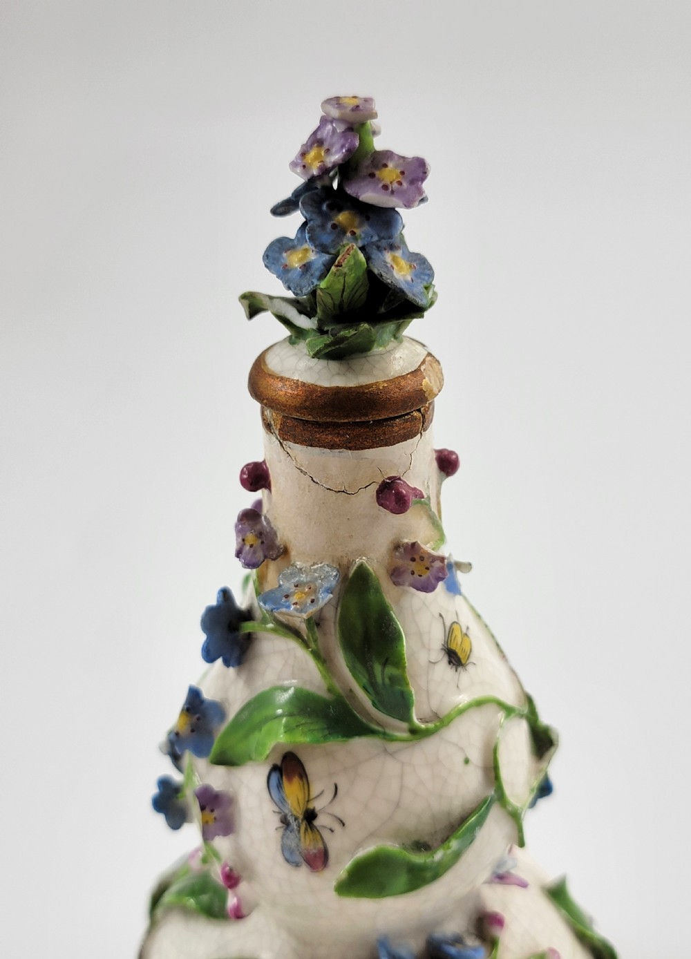 A gourd-shaped white porcelain scent bottle decorated with applied forget-me-not flowers, green vines, hand-painted insects, and a floral stopper. View VII