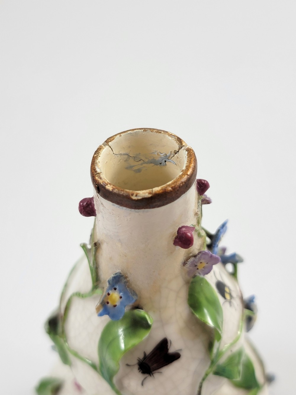 A gourd-shaped white porcelain scent bottle decorated with applied forget-me-not flowers, green vines, hand-painted insects, and a floral stopper. View VIII