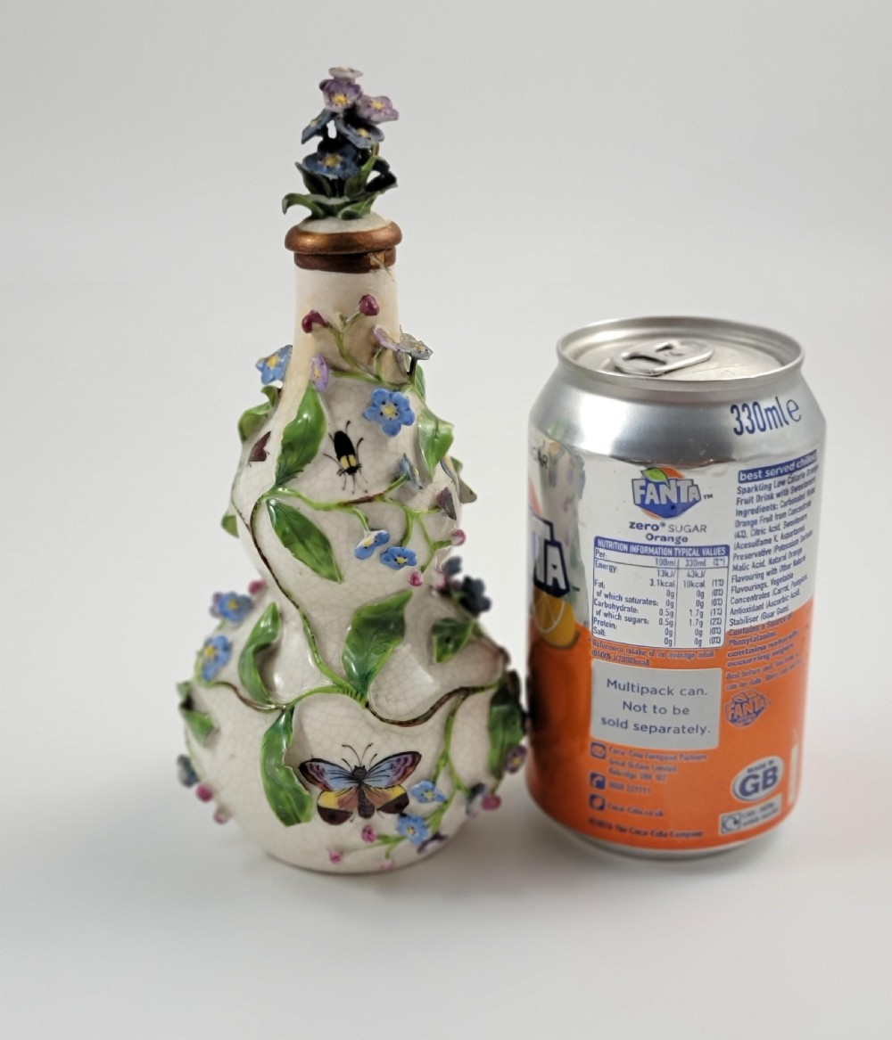A gourd-shaped white porcelain scent bottle decorated with applied forget-me-not flowers, green vines, hand-painted insects, and a floral stopper. View XII