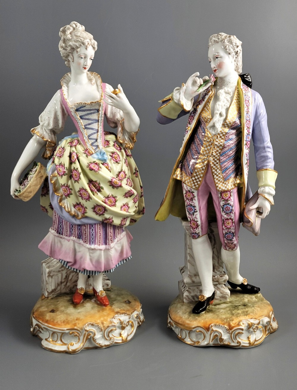 A pair of 18th-century German hard-paste porcelain figurines depicting a gentleman and lady in court dress on gilded bases.