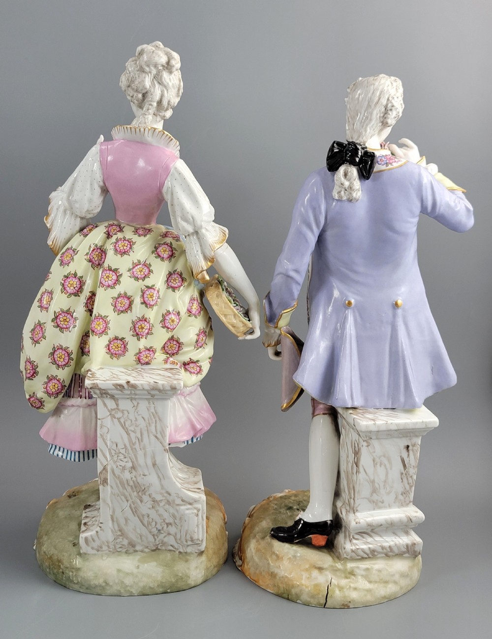 A pair of 18th-century German hard-paste porcelain figurines depicting a gentleman and lady in court dress on gilded bases. View V