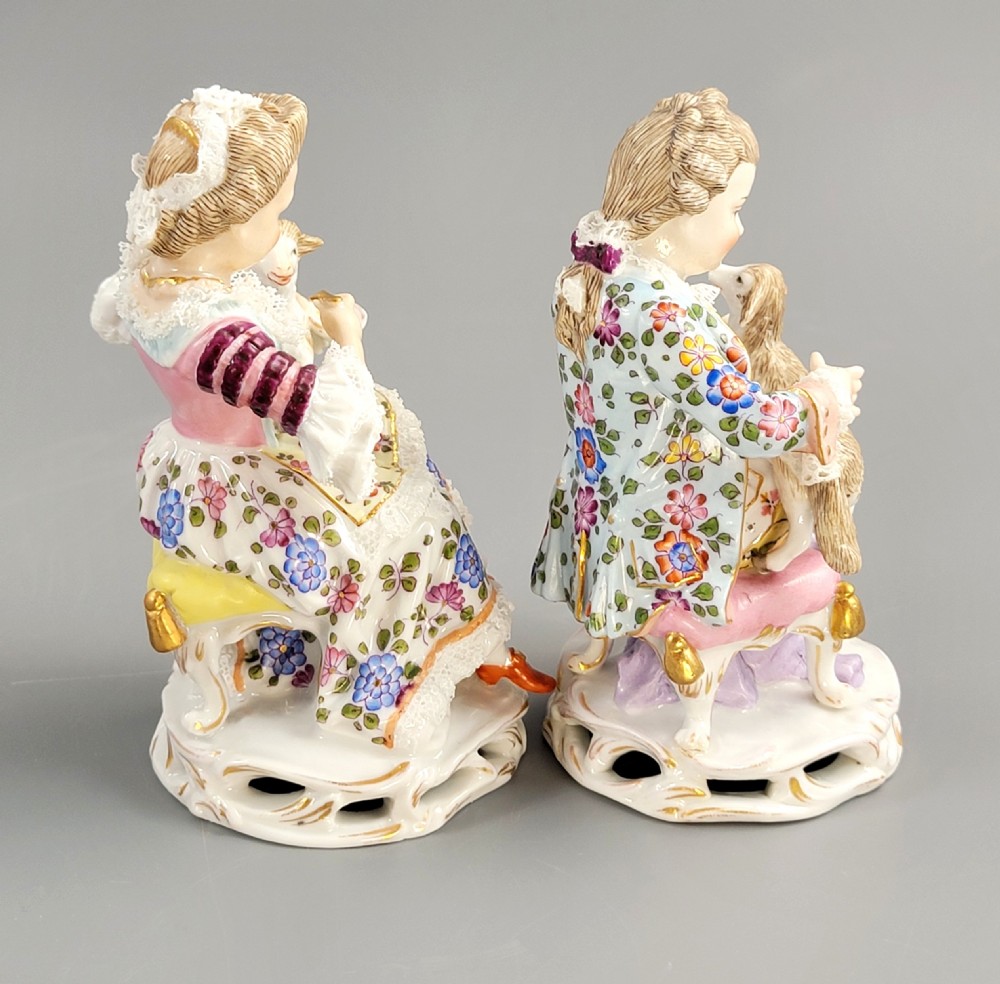 A pair of late 19th-century Sitzendorf porcelain figurines depicting a boy and girl in 18th-century clothing seated with pet lambs on gilded scrollwork bases. View IV