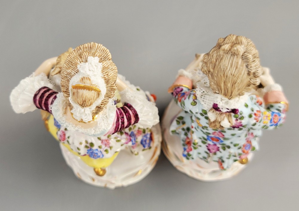 A pair of late 19th-century Sitzendorf porcelain figurines depicting a boy and girl in 18th-century clothing seated with pet lambs on gilded scrollwork bases. View V