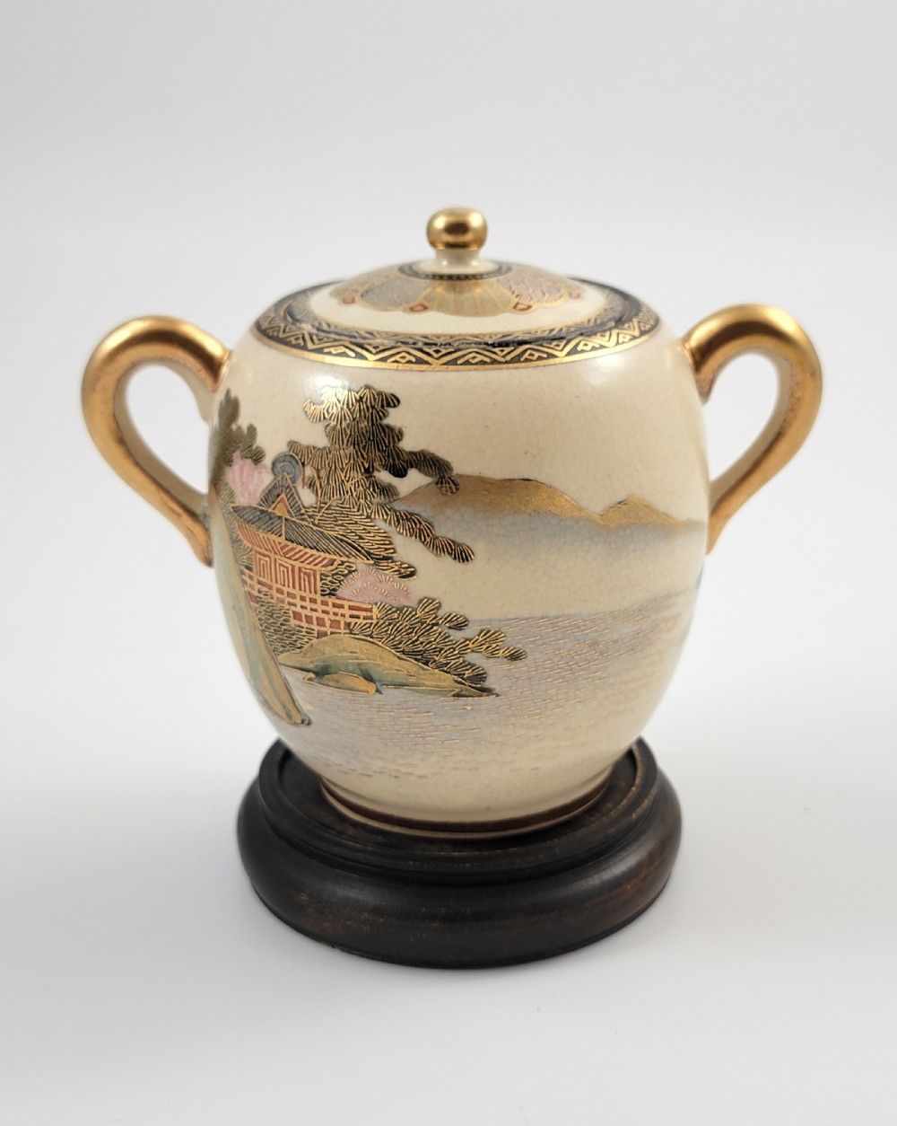 A lidded Japanese Satsuma ceramic sugar bowl with two gilt handles, crackle glaze, and hand-painted figures in a landscape. View IV
