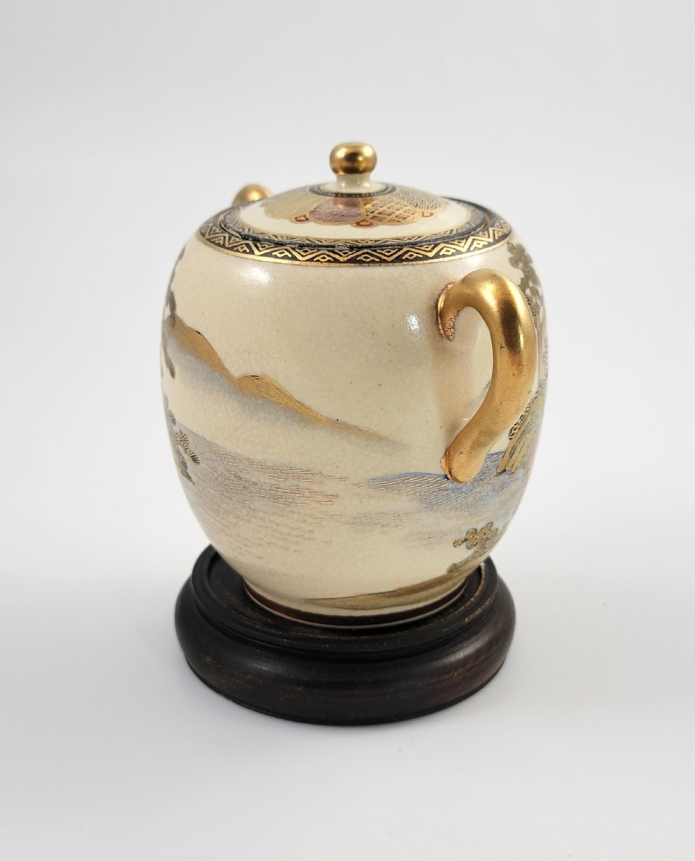 A lidded Japanese Satsuma ceramic sugar bowl with two gilt handles, crackle glaze, and hand-painted figures in a landscape. View V