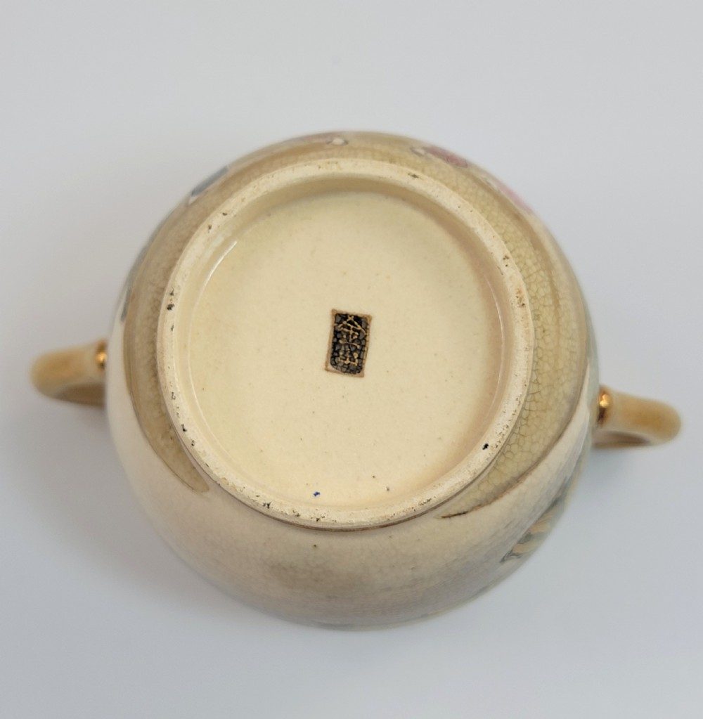 A lidded Japanese Satsuma ceramic sugar bowl with two gilt handles, crackle glaze, and hand-painted figures in a landscape. View IX