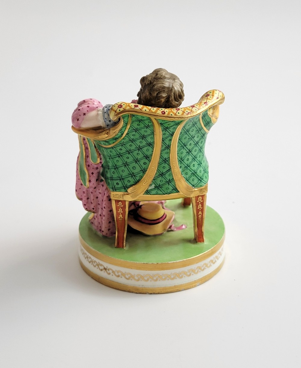 An 18th-century Derby soft-paste porcelain figurine depicting a seated woman in a colourful dress reclining on a gilded armchair. View III